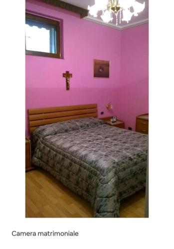 ein Schlafzimmer mit einem Bett und einem Kreuz an der Wand in der Unterkunft B&b L'Oasi del Vulture in Rapolla