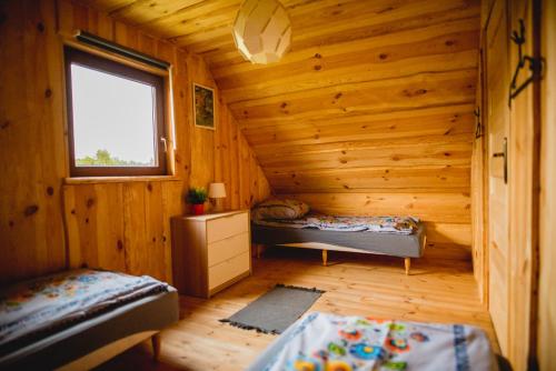 a room with two beds in a log cabin at Domki PAGAJ in Zwierzyniec