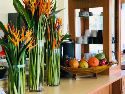 a counter with vases filled with flowers and a bowl of fruit at Phurua Inn ภูเรือ อินน์ in Loei