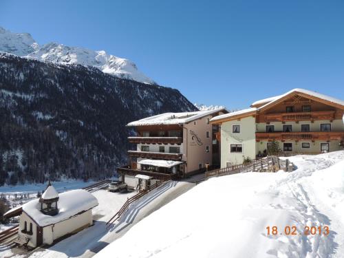 a building in the snow with a mountain in the background at Pension Winnebach in Längenfeld