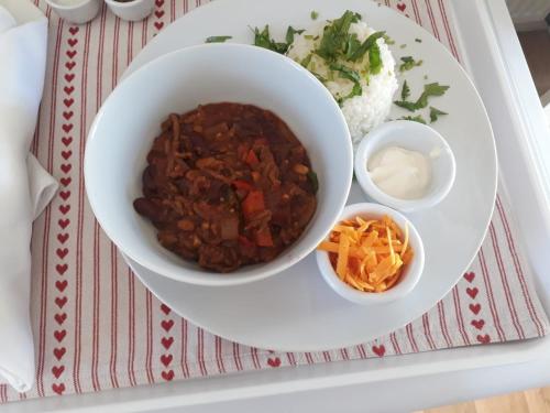 a white plate with a bowl of chili and rice at Rural Farmhouse in Poughill