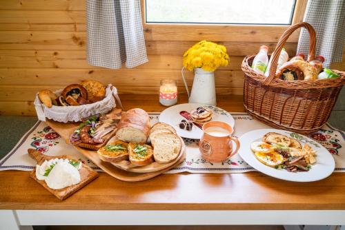 a table with plates of food and a basket of bread at Salaš Syrex in Zázrivá