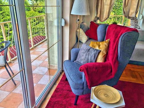 a living room with a blue chair with a red blanket at Villa Borostyán in Tihany
