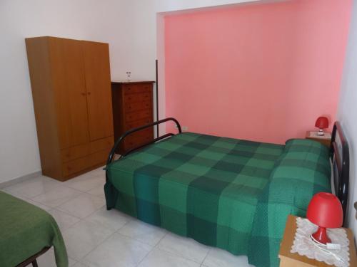 a bedroom with a bed with a green checkered blanket at Casa Orchidea in Lipari