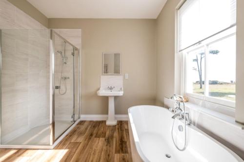 a bathroom with a tub and a shower and a sink at The Dower Lodge in Sizewell