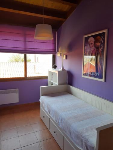 1 dormitorio con paredes moradas y 1 cama grande en Vistas al Sueve, en Colunga