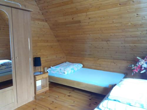 a small room with a bed in a wooden cabin at Olszanka in Olchowiec