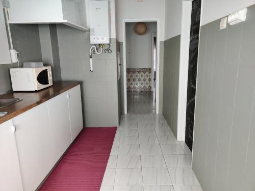 une cuisine avec des placards blancs et un tapis rouge dans l'établissement Vasco Santana Guesthouse, à Odivelas