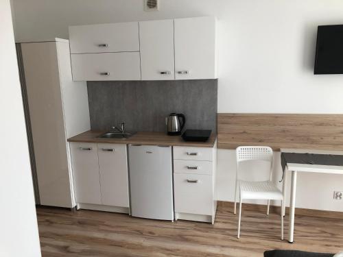 a kitchen with white cabinets and a table and chairs at Willa Wena in Ustka