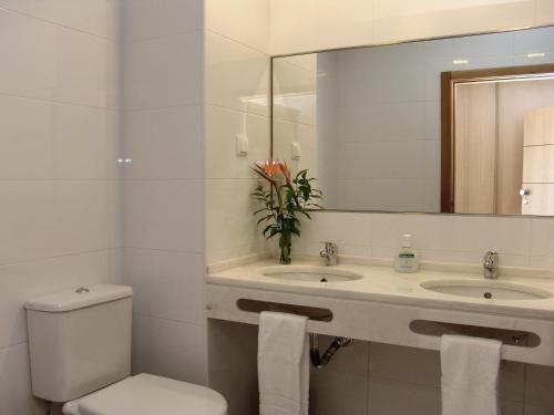 a bathroom with a toilet and two sinks and a mirror at Apartamentos Turisticos Monte da Vinha II in Albufeira