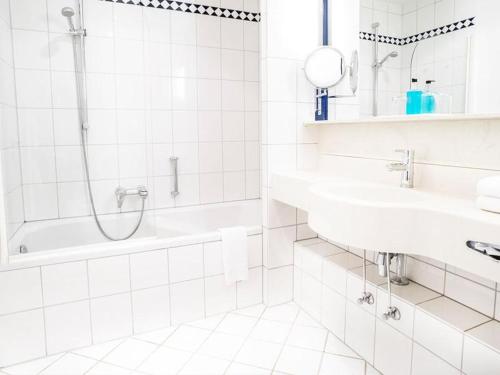 a white bathroom with two sinks and a shower at Hennedamm Hotel in Meschede