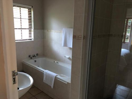 a bathroom with a tub and a toilet and a sink at Gooderson Knysna Chalets in Knysna