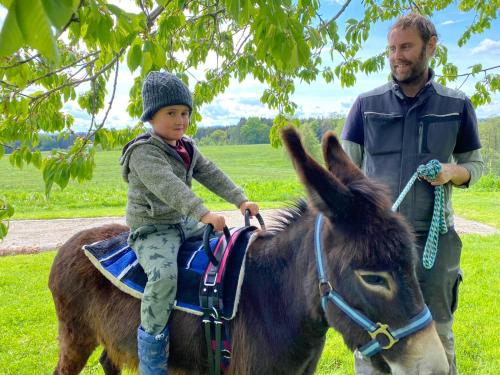 a young child sitting on a donkey with a man at Wastlbauer in Mattsee