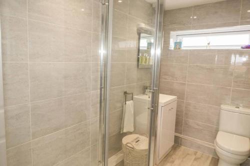 a bathroom with a toilet and a glass shower at Hegarty's cottage at Trevarrian Lodge in Mawgan Porth