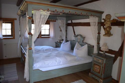 a bedroom with a four poster bed with white sheets at zum Frongut in Burgstaedt