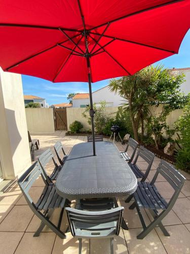 a table and chairs with a red umbrella at Maison de vacance proche de la mer in Les Sables-dʼOlonne