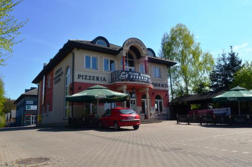 a red car parked in front of a building with umbrellas at KEISA APARTRooms in Nowy Sącz