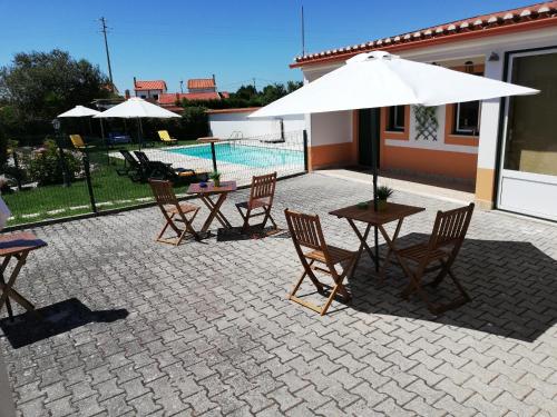 a patio with a table and chairs and an umbrella at Quinta Sao Martinho in Reguengo Grande