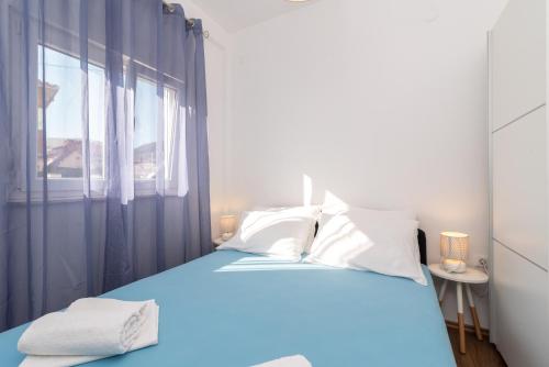 Un dormitorio con una cama azul y una ventana en Apartments Bruna Trogir en Trogir