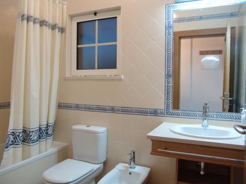 uma casa de banho com um WC, um lavatório e um espelho. em Apartamentos Monte da Vinha I em Albufeira