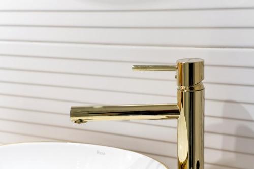 a gold bathroom sink faucet in front of a wall at Apartament Perła Pienin in Dębno