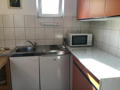 una pequeña cocina con fregadero y microondas en Mandala apartman en Dömös