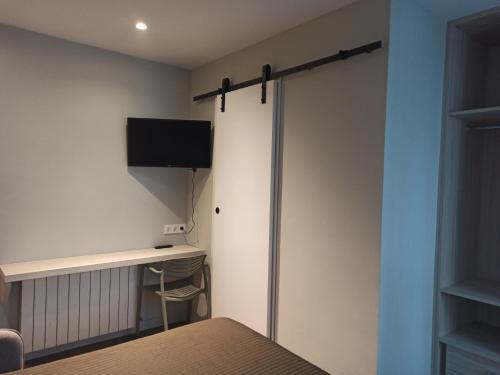 a room with a bed and a tv on a wall at Bearan Bar & Rooms in Pamplona