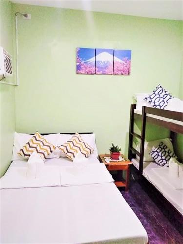 a bedroom with two white beds and a table at Fil-Can Hostel Coron in Coron