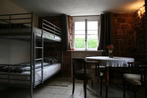 a room with two bunk beds and a table and a window at Chambre d'Hotes Petit Arnsbourg in Obersteinbach