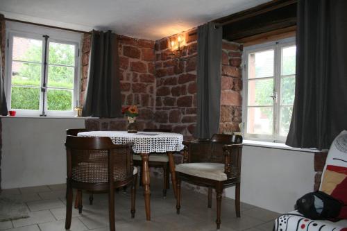 une salle à manger avec une table, des chaises et des fenêtres dans l'établissement Chambre d'Hotes Petit Arnsbourg, à Obersteinbach