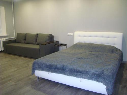 a bedroom with a bed and a couch at Квартира студия в центре Чернигова wi-fi in Chernihiv