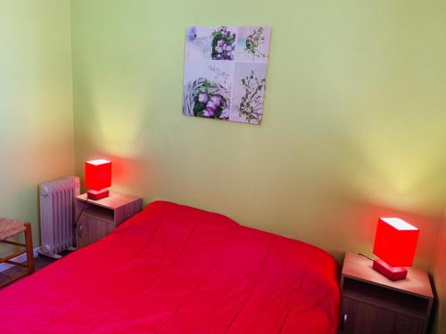 a bedroom with a red bed and two red lamps at le grand large in Sète