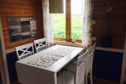 einen weißen Tisch und Stühle in einem Zimmer mit Fenster in der Unterkunft Grandfathers house at the end of Europe, Varanger in Havningberg