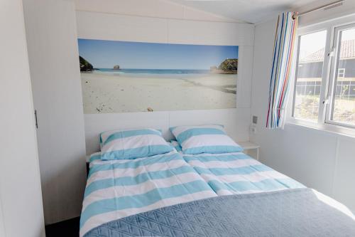 a bedroom with a bed with a picture of the beach at Noordkop vakanties in Westerland