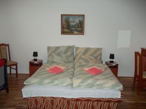 a bed in a room with two red cards on it at Szikla Vendégház in Istenmezeje