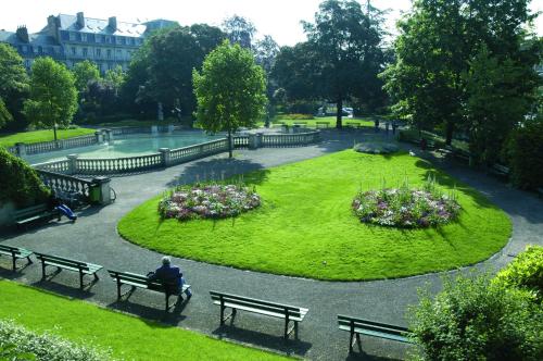 un homme assis sur un banc dans un parc dans l'établissement Appart Hotel Montchapet Dijon Centre, à Dijon