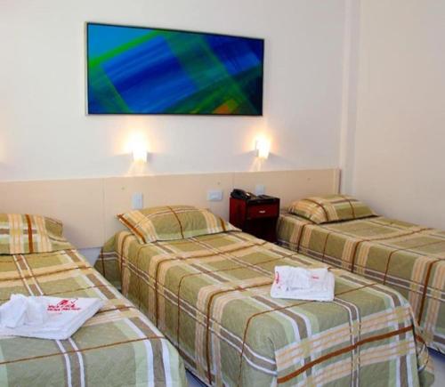 a hotel room with two beds and a tv on the wall at Hotel Pampulha Palace in Belo Horizonte