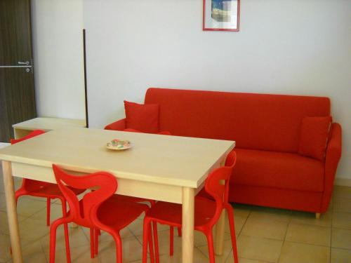 a table with four red chairs and a couch at Zagare Residence in Rodi Garganico