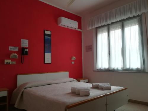 a red bedroom with a bed with two towels on it at Hotel Pigalle in Rimini
