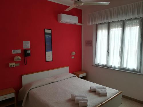 a bedroom with red walls and a bed with two towels at Hotel Pigalle in Rimini