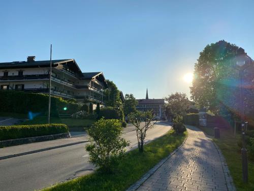 a street with a building and the sun in the sky at Lea am See - Bio Design Appartement in Tegernsee