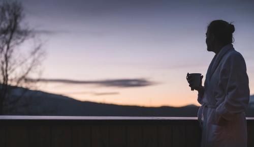 a man standing on a fence with a cup in his hand at Niedermairhof in Brunico