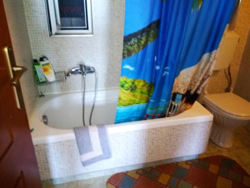 y baño con bañera y cortina de ducha azul. en Riza Falasarna Apartments 50m2, en Falasarna