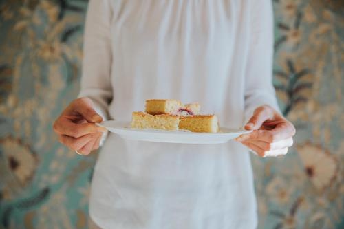a person holding a plate with a piece of cake at Niedermairhof in Brunico