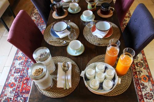 una mesa de madera con platos de comida y vasos de zumo de naranja en Manoir de Beauregard - Cunault, en Trèves-Cunault