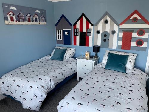 1 dormitorio con 2 camas y un mural de casas en Waterside Guesthouse, en Dymchurch