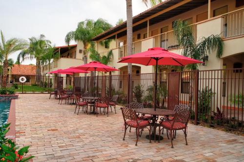 a patio with tables and chairs with red umbrellas at The Bungalows on Shary in McAllen