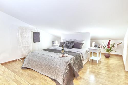 Un dormitorio blanco con una cama y un jarrón de flores en Exclusive Apartments Lisbon - Charneca de Caparica en Charneca
