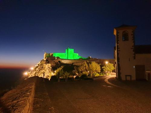 a building with green lights on top of it at night at Casa O Arco Alojamento Local in Marvão