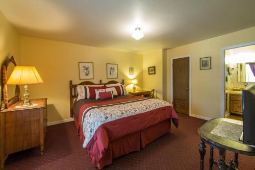 Schlafzimmer mit einem Bett, einem Tisch und einem TV in der Unterkunft Historic Cary House Hotel in Placerville